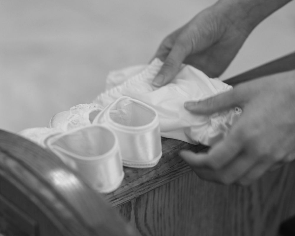 White baptismal booties placed on wooden surface during ceremony.