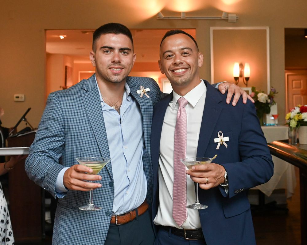 Two guests enjoying drinks at a formal event in an elegantly lit venue.