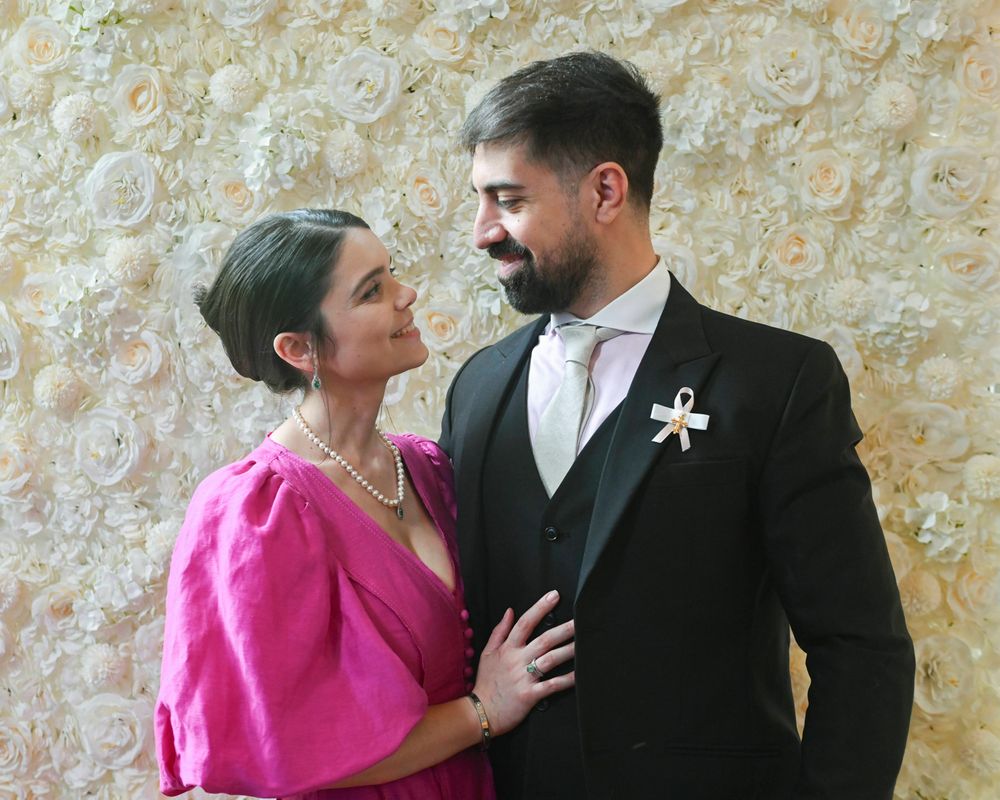 A couple poses against a floral backdrop at a formal celebration.