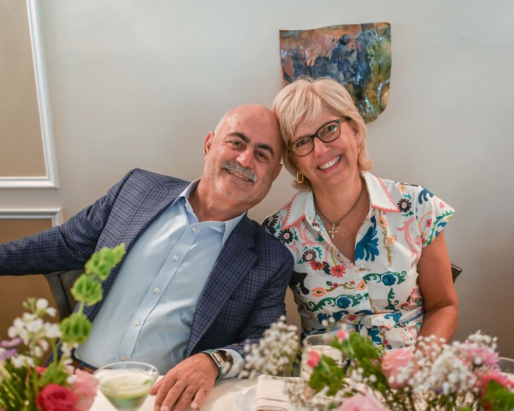 A couple sharing an intimate moment at a celebration surrounded by floral decorations.