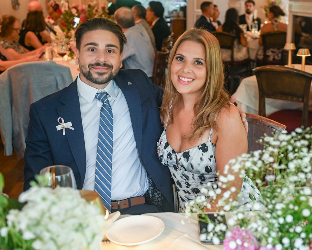 A couple sitting at an elegant reception table decorated with white floral centerpieces.
