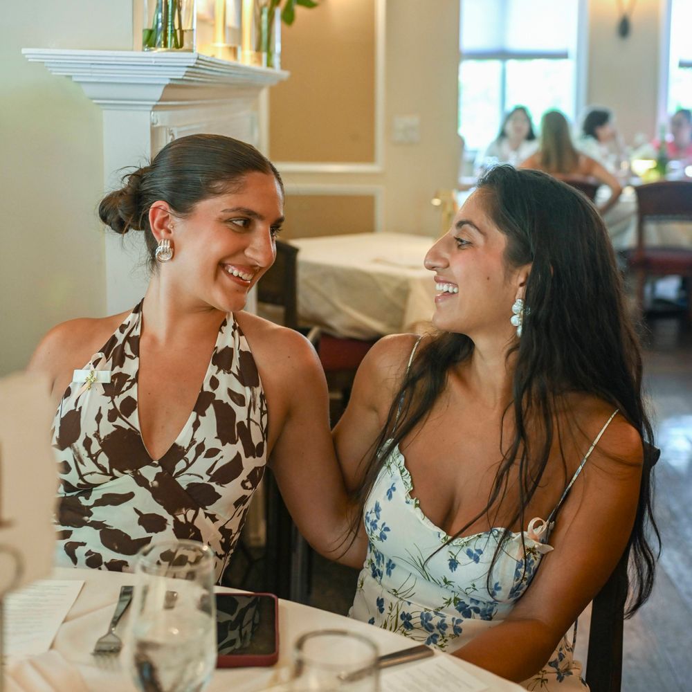 Two guests sharing a candid laughing moment at an elegant dining table.