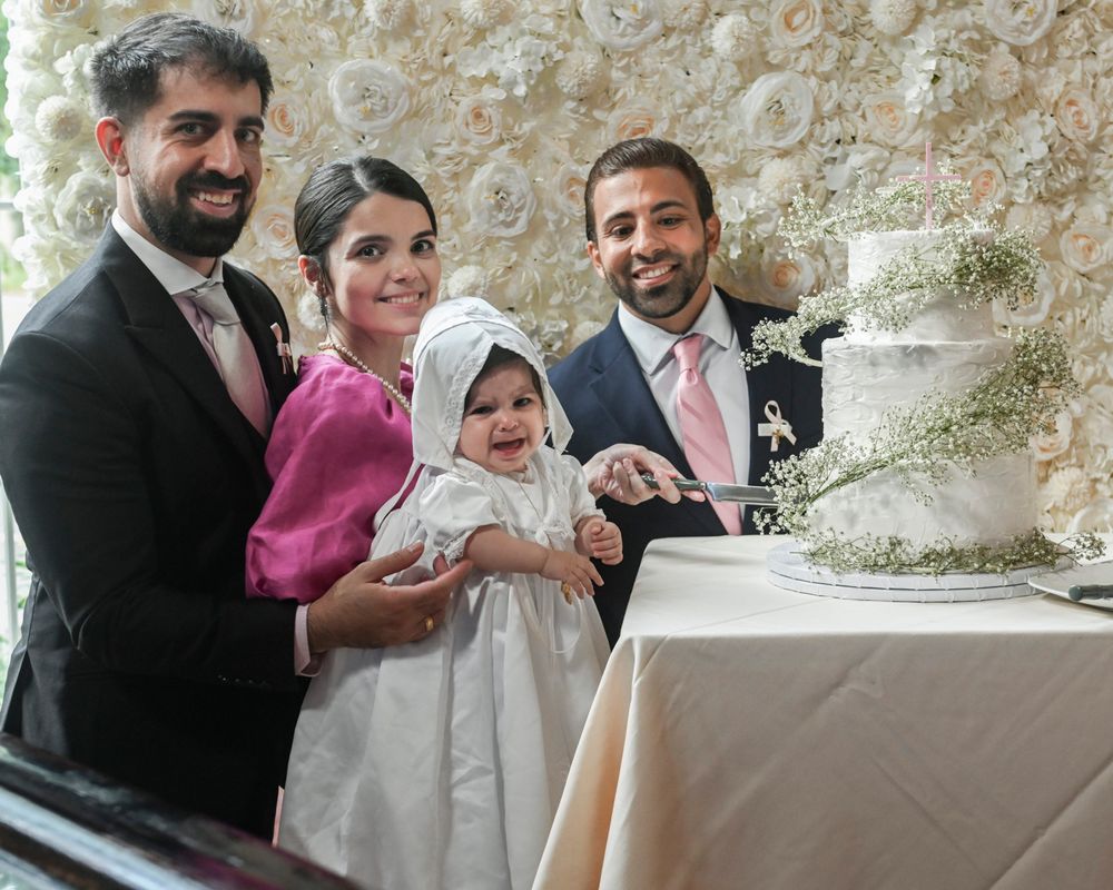 A family gathering around an elegant white wedding cake at a formal celebration.