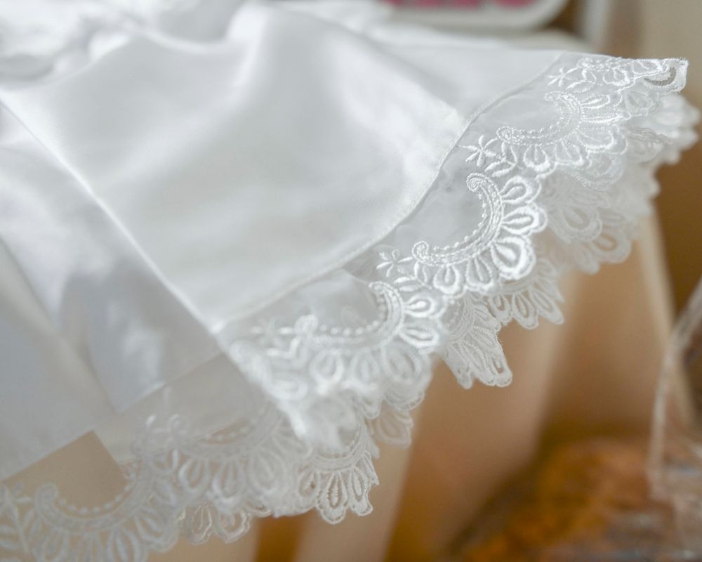 Close-up detail of delicate white lace trim on a formal garment.