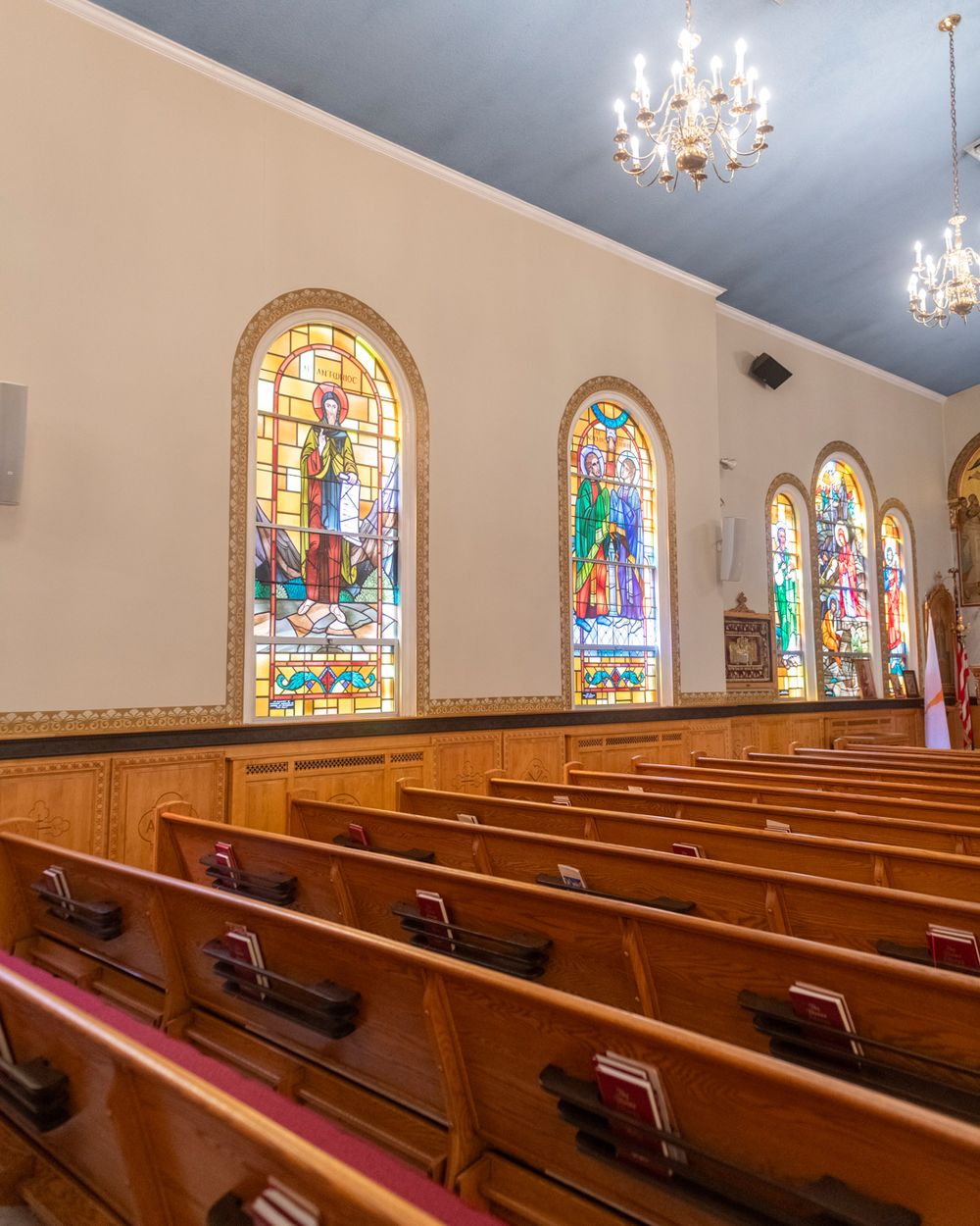 Church interior with wooden pews and beautiful stained glass windows depicting religious scenes.