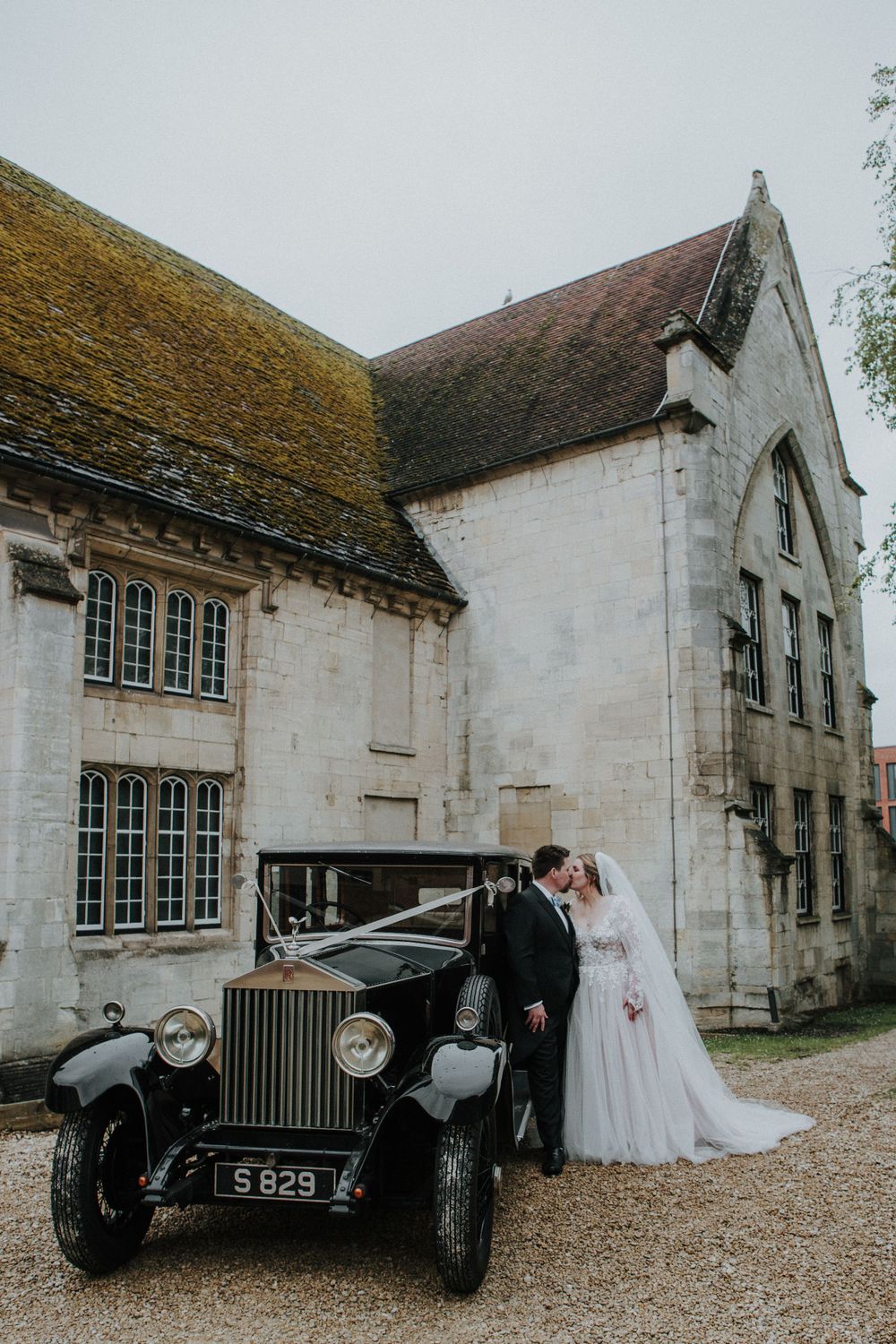 Classic Rolls Royce parked in front of a historic stone church during a wedding celebration. Blackfriars Priory
