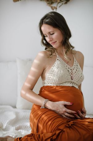 Boho maternity photo featuring crochet top and flowing rust-colored skirt.