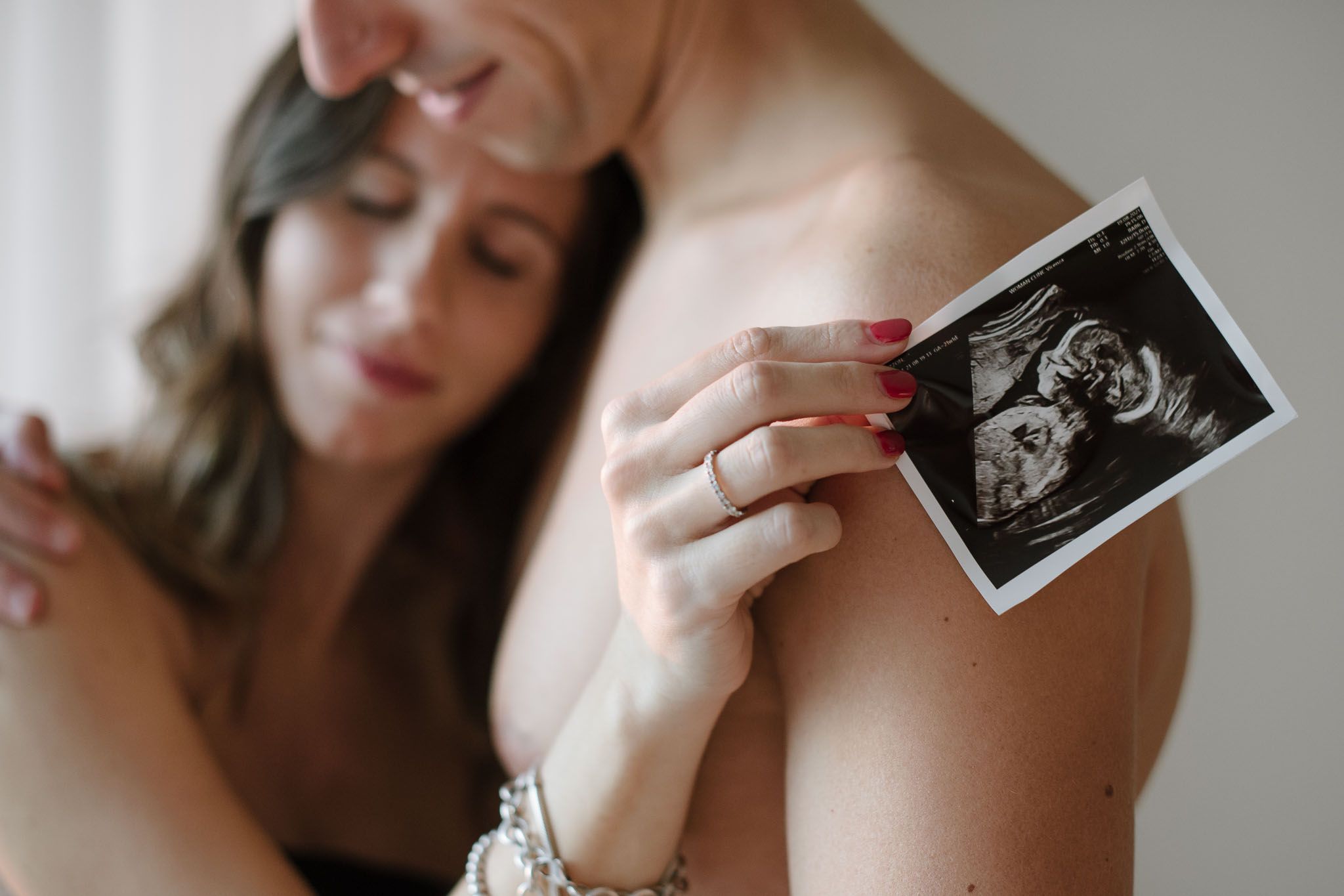 An intimate maternity moment showing hands holding an ultrasound photo.