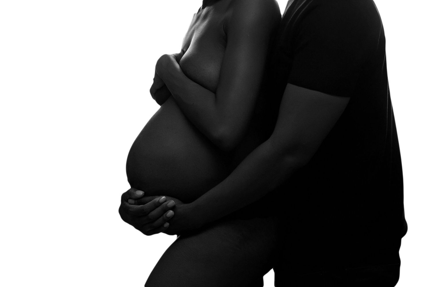 faceless high key artful pregnant nude of a pregnant woman and her partner in a loving embrace black and white