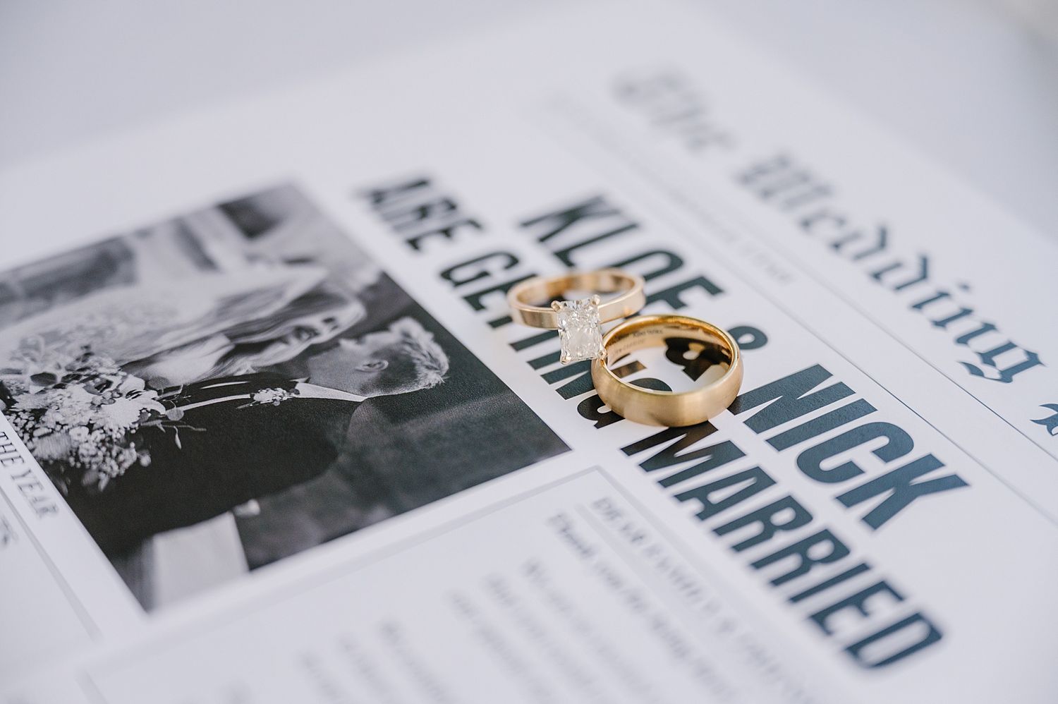 Gold wedding ring rests on top of black and white wedding photos and text in a printed album or magazine.
