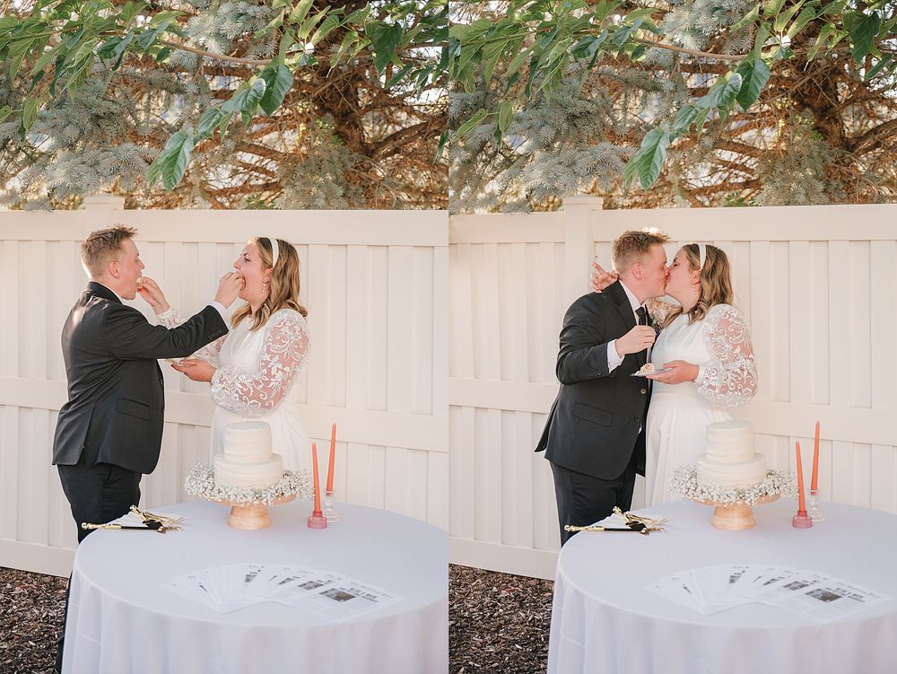 A couple shares a romantic moment while cutting their wedding cake at an outdoor reception table.