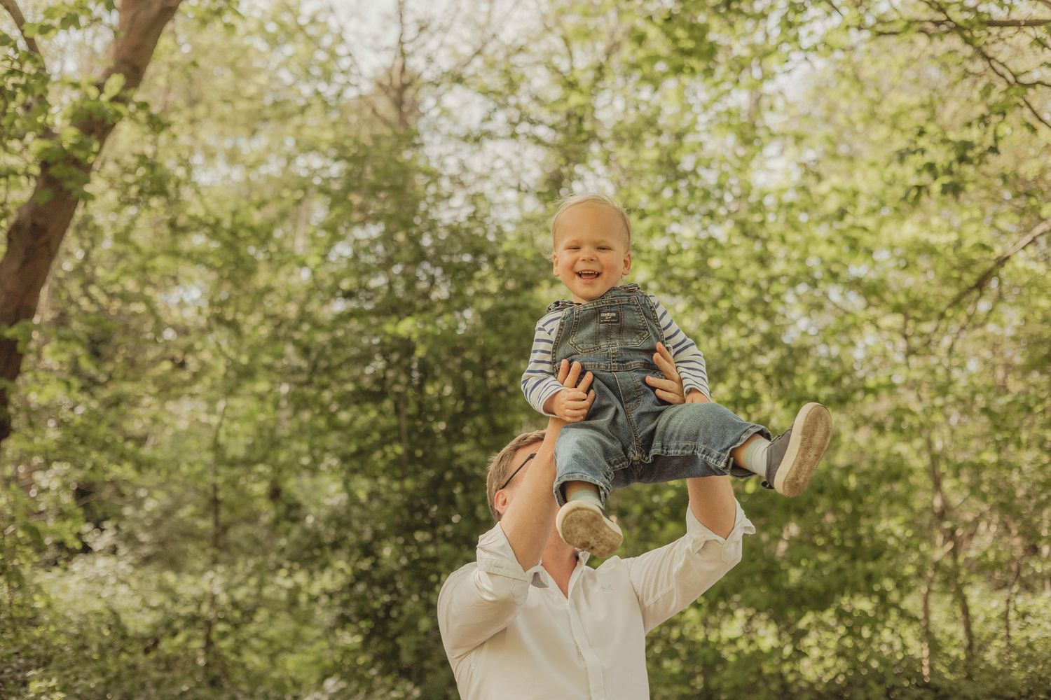 dad throwing baby in the air and laughing, on Wandsworth common