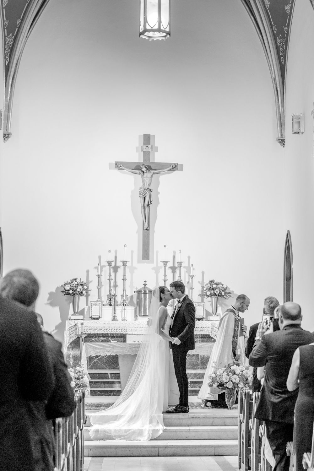 Black and white capture of a wedding ceremony in a traditional church setting with gothic architecture.