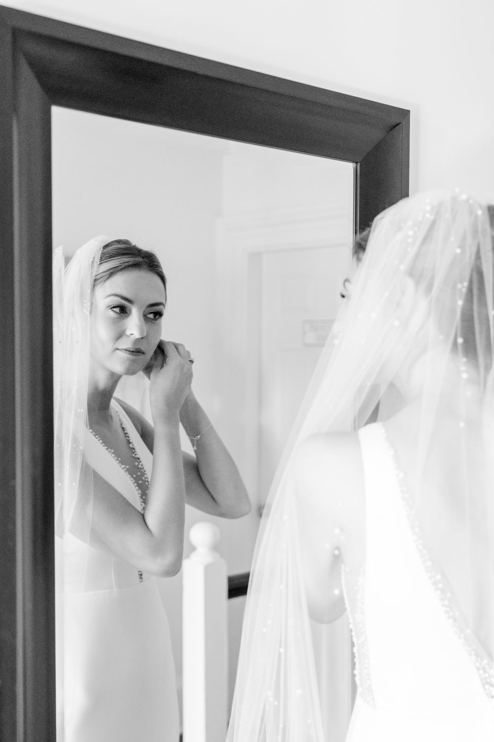 Elegant bridal preparation moment captured in mirror reflection with veil detail.