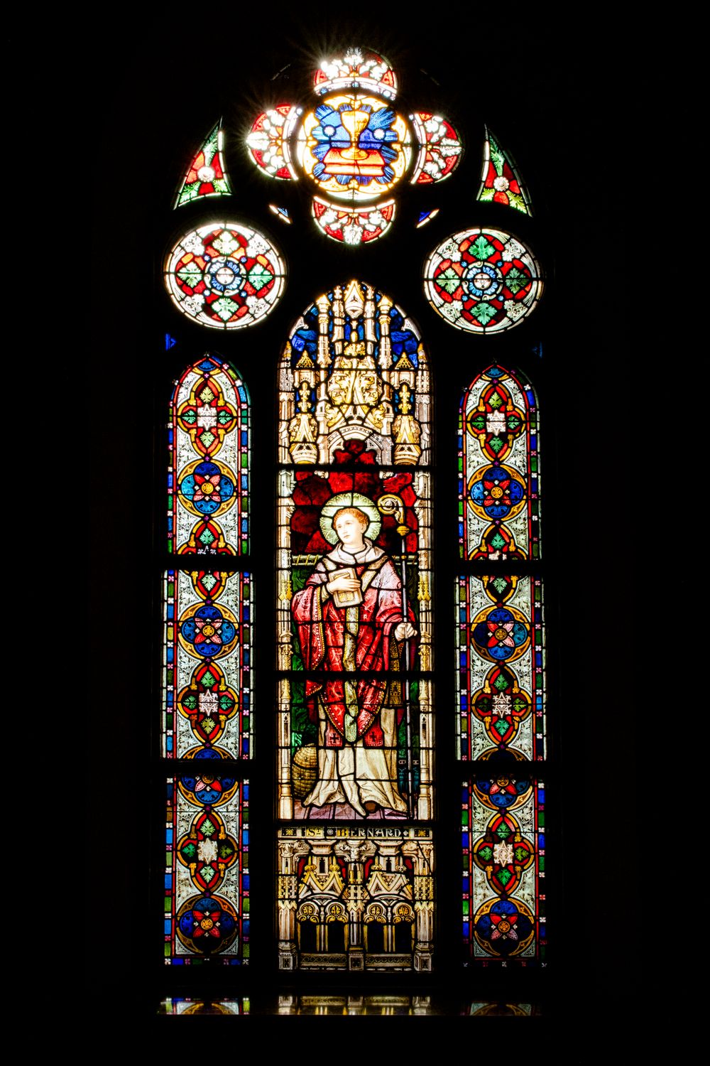 Ornate stained glass church window featuring religious iconography and decorative patterns.