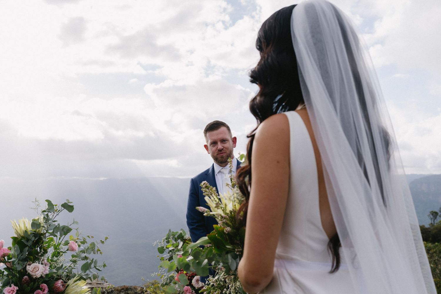 Intimate outdoor wedding ceremony with mountain views and floral arrangements.