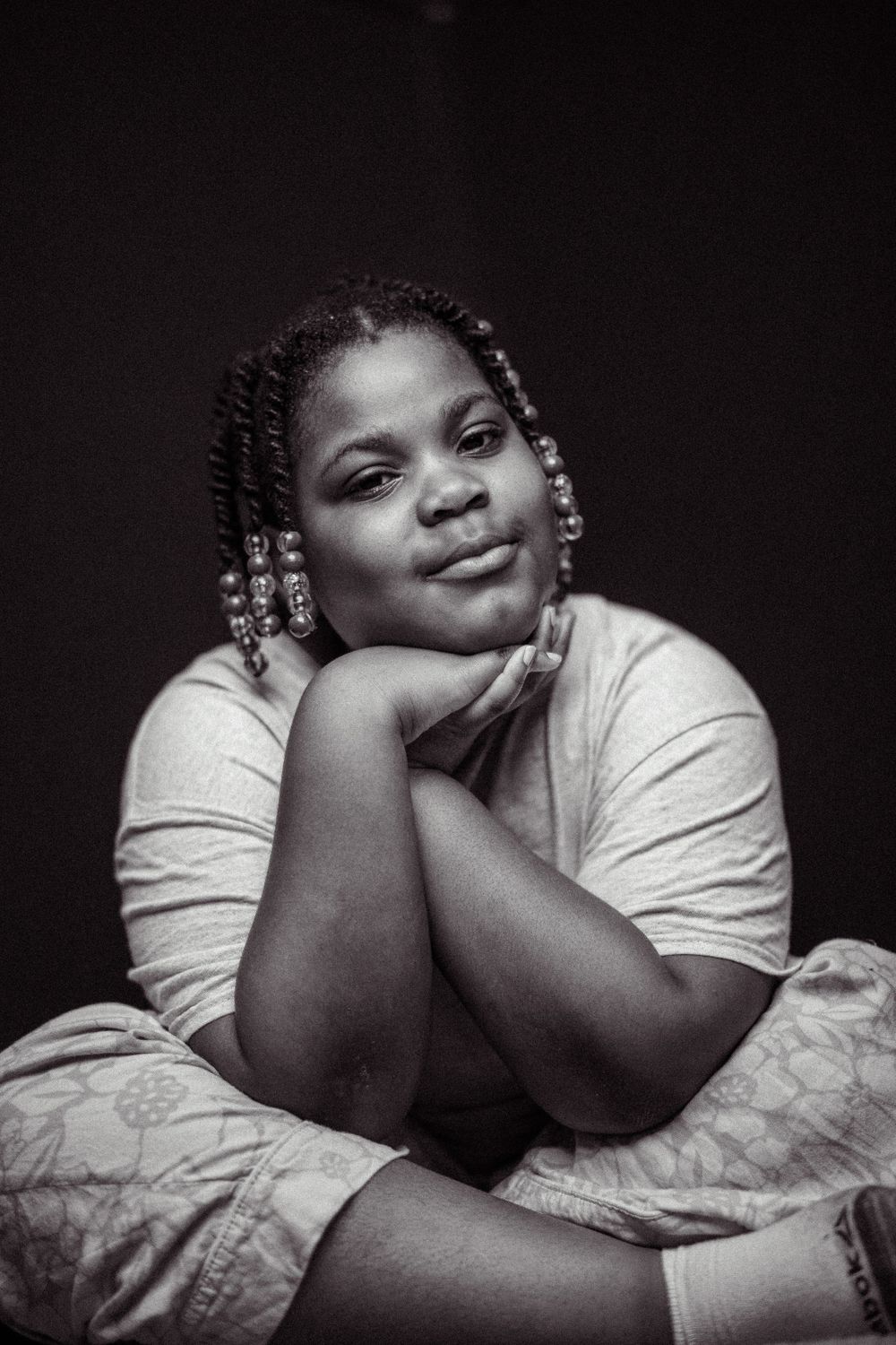 Artistic black and white portrait showing relaxed pose against dark backdrop.