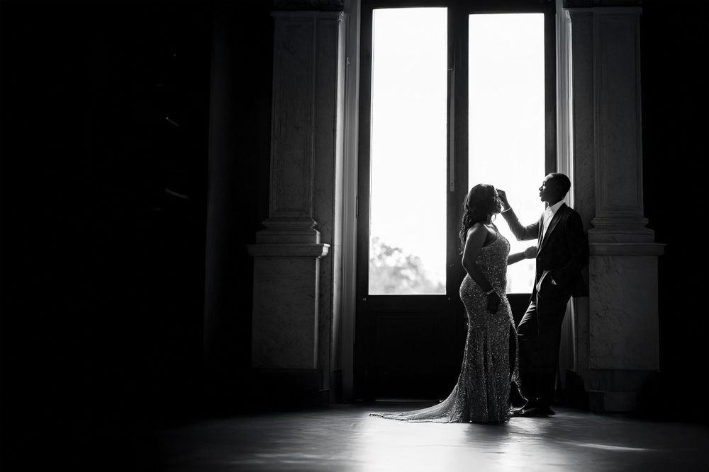 Silhouetted figures framed in bright window creating dramatic contrast in dark room.