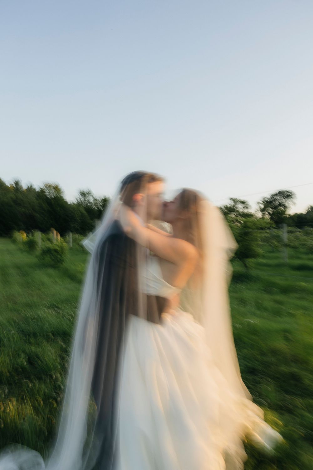 Artistic motion blur wedding photos in a green summer field at dusk.
