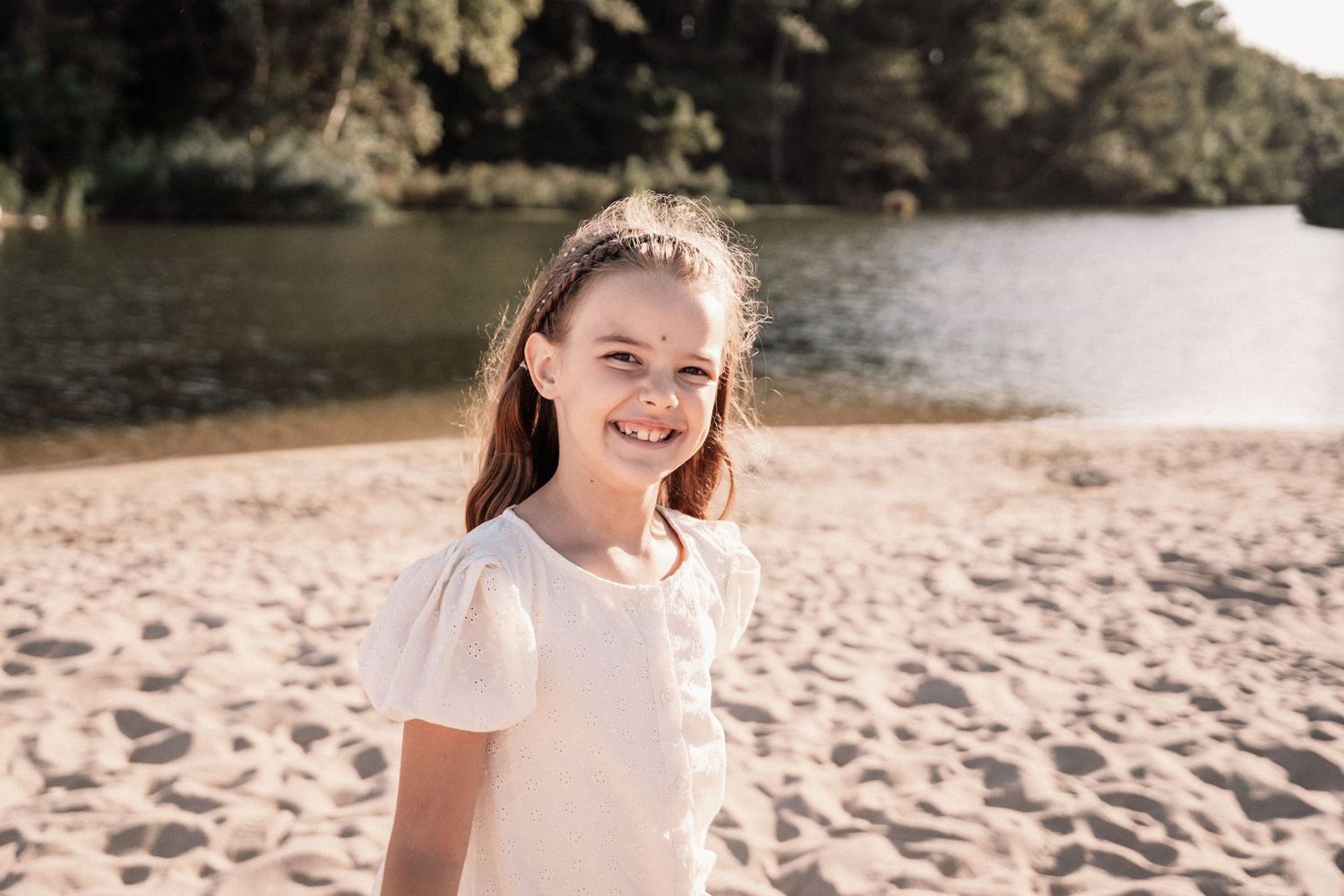 Beach photoshoot captures candid moments of family members in white outfits.