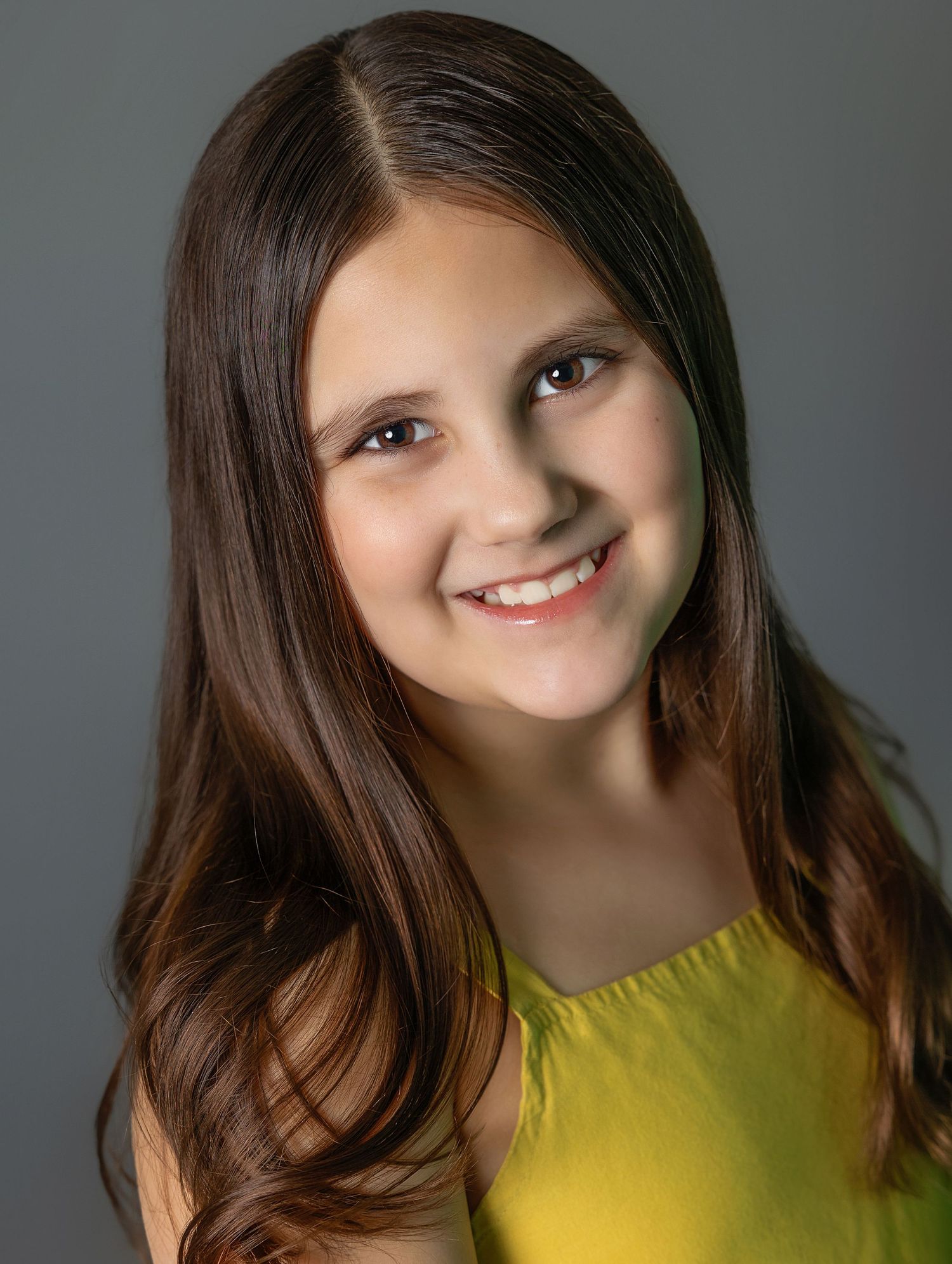 Studio portrait with natural lighting featuring yellow top and long brown hair.