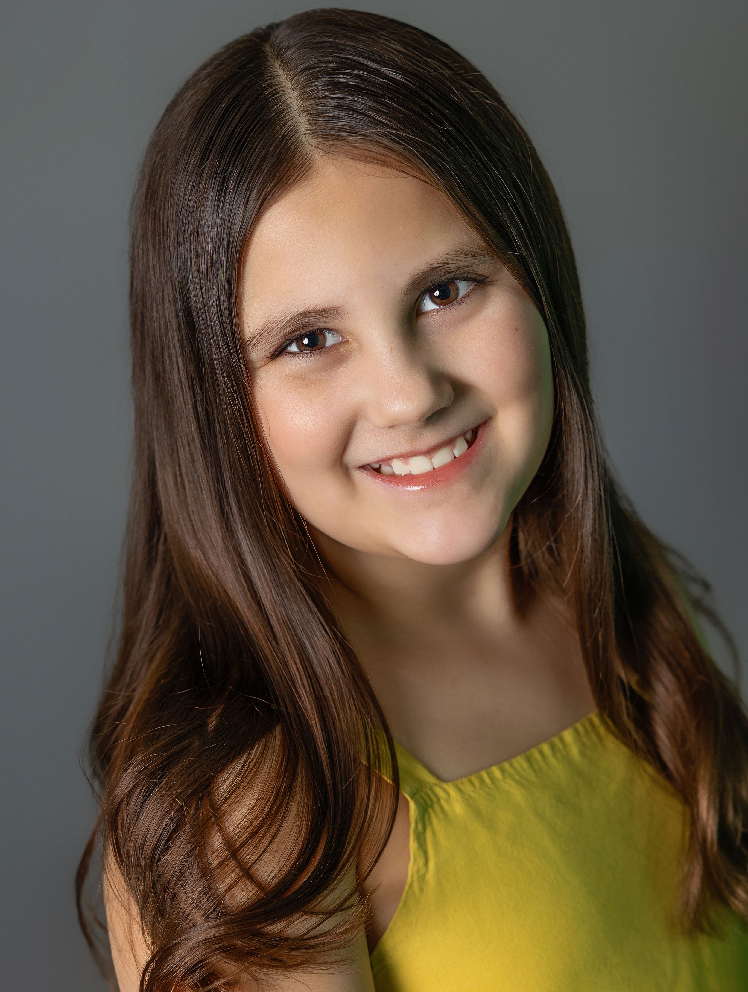 Studio portrait with natural lighting featuring yellow top and long brown hair.