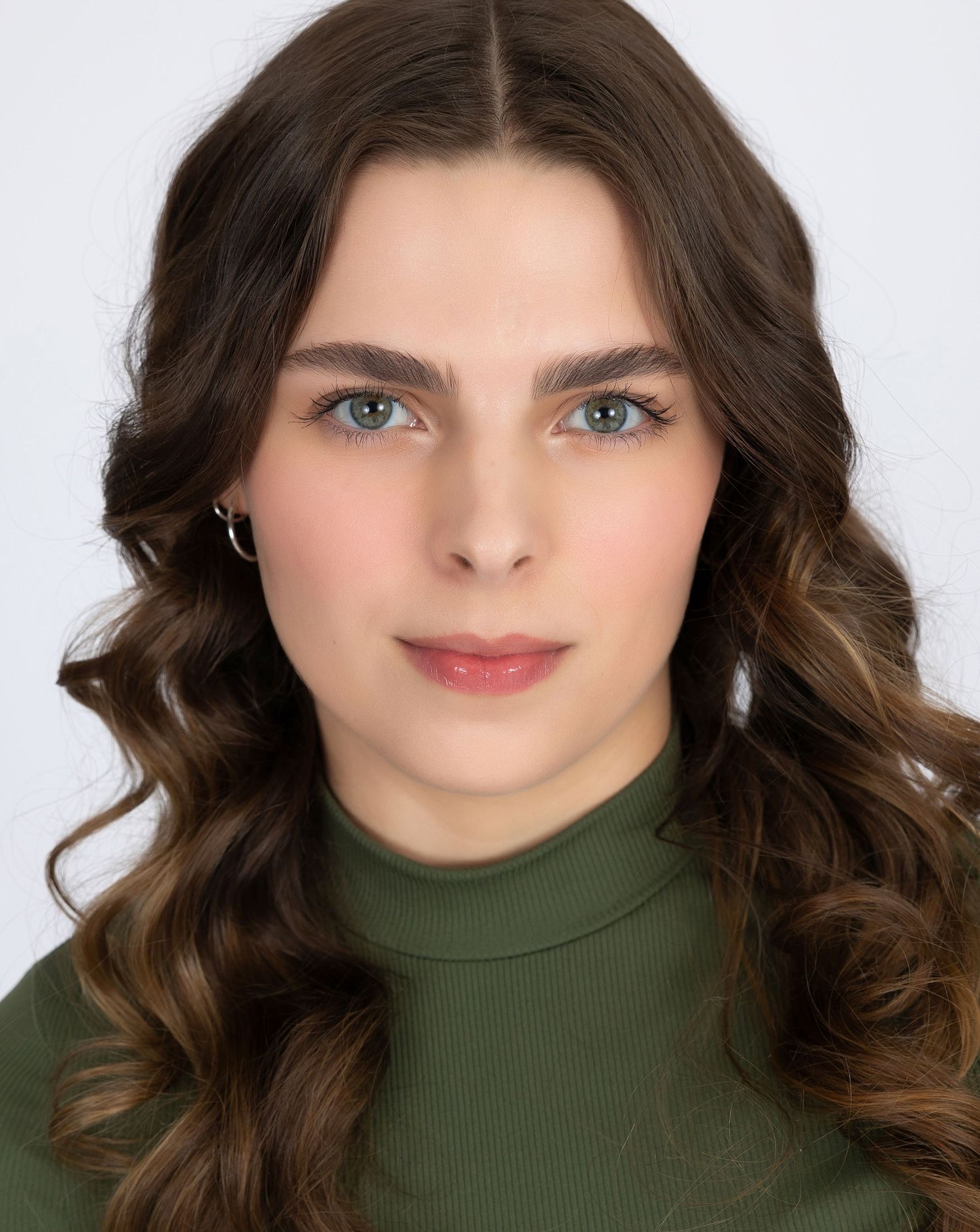Professional headshot featuring someone in green turtleneck with long wavy hair.