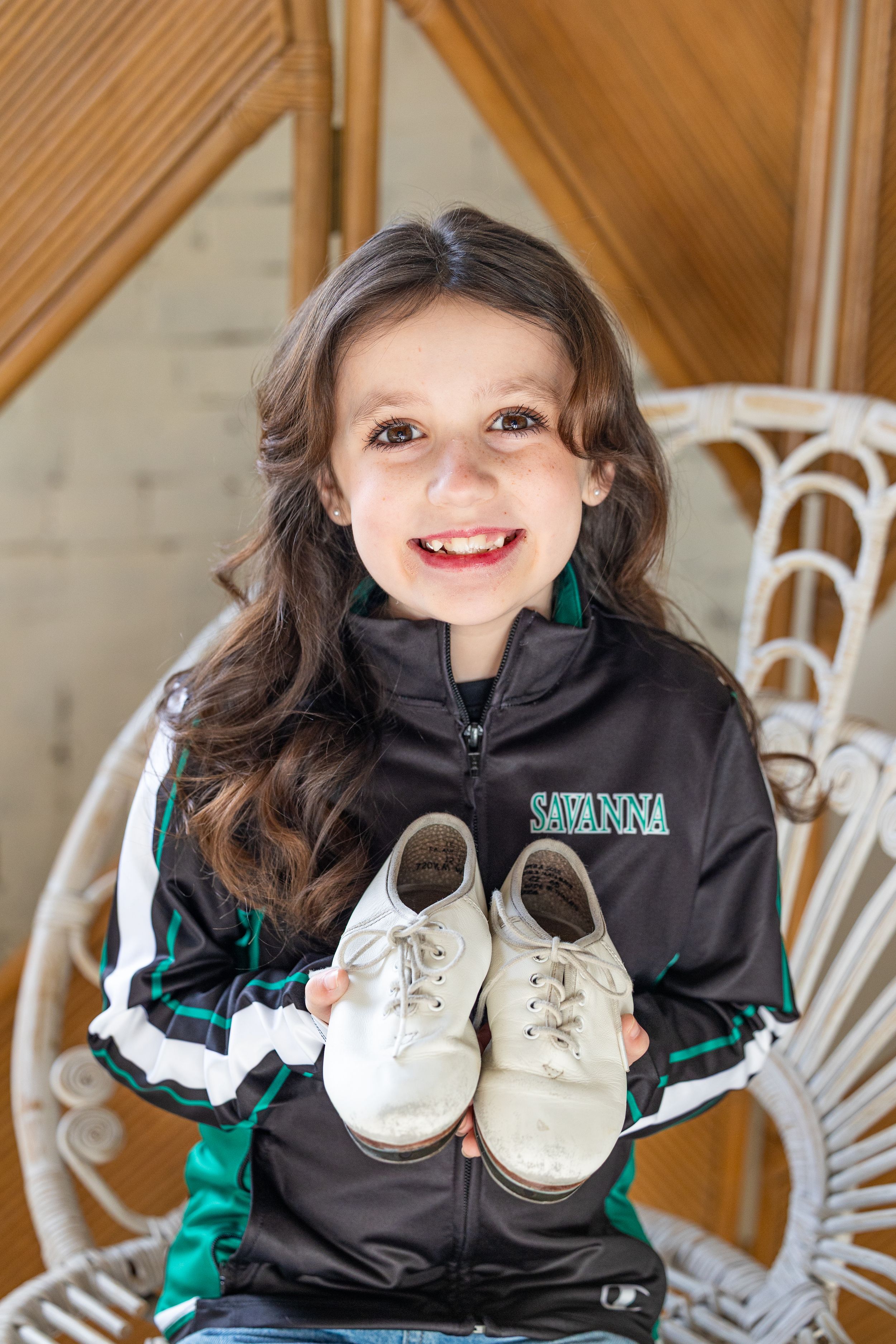 A series of photos showing someone in a black jacket holding up small white baby shoes against a wooden background.