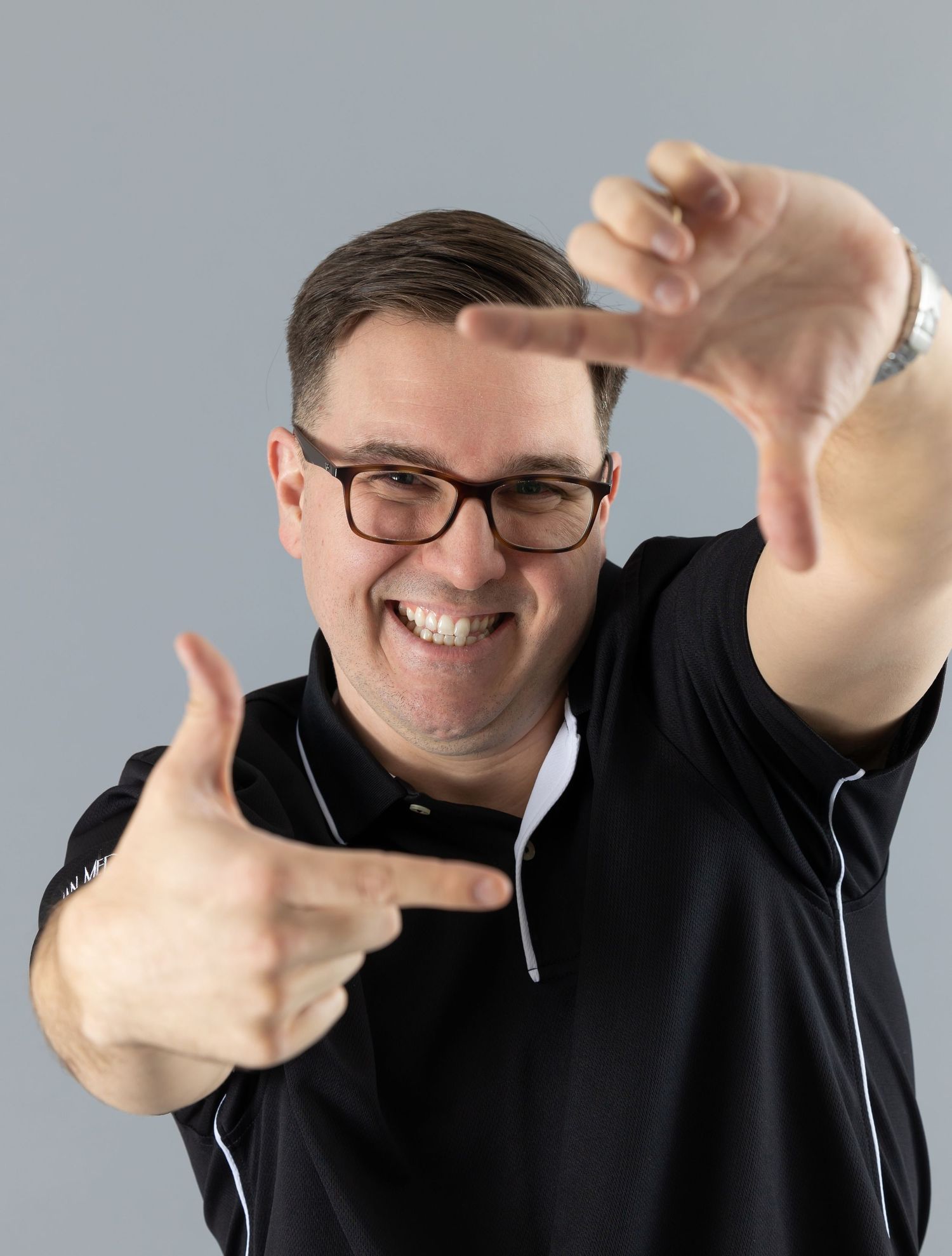 Energetic portrait of someone making a frame gesture with their hands.