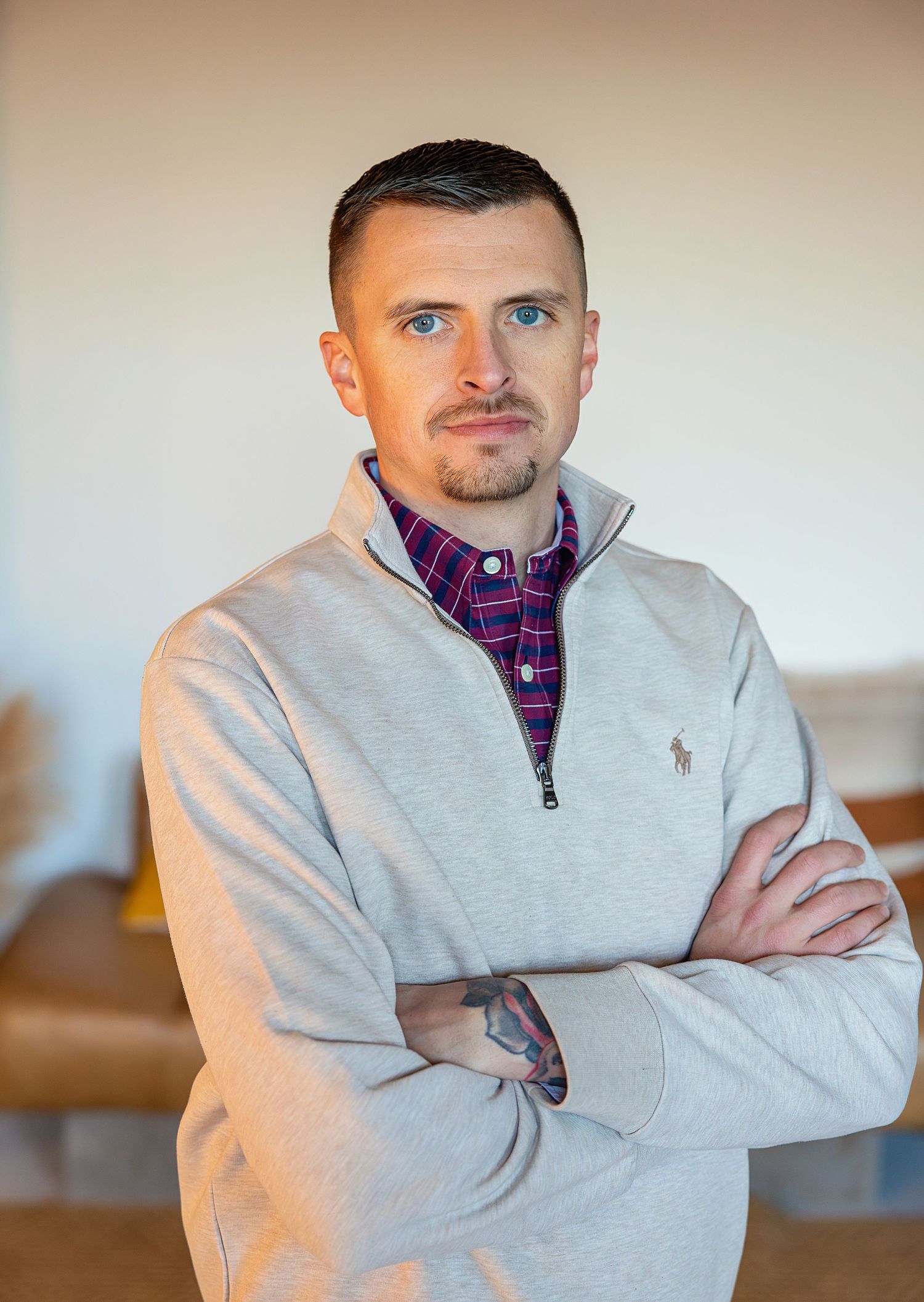 Business casual portrait of person in grey quarter-zip and plaid shirt.