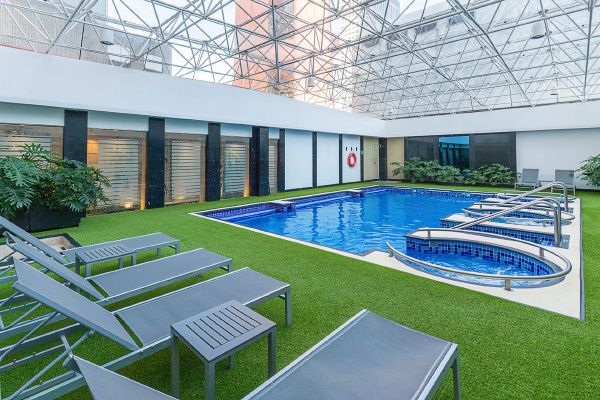 Luxury indoor swimming pool with loungers and artificial turf surroundings. Barcelo Mexico City Reforma.