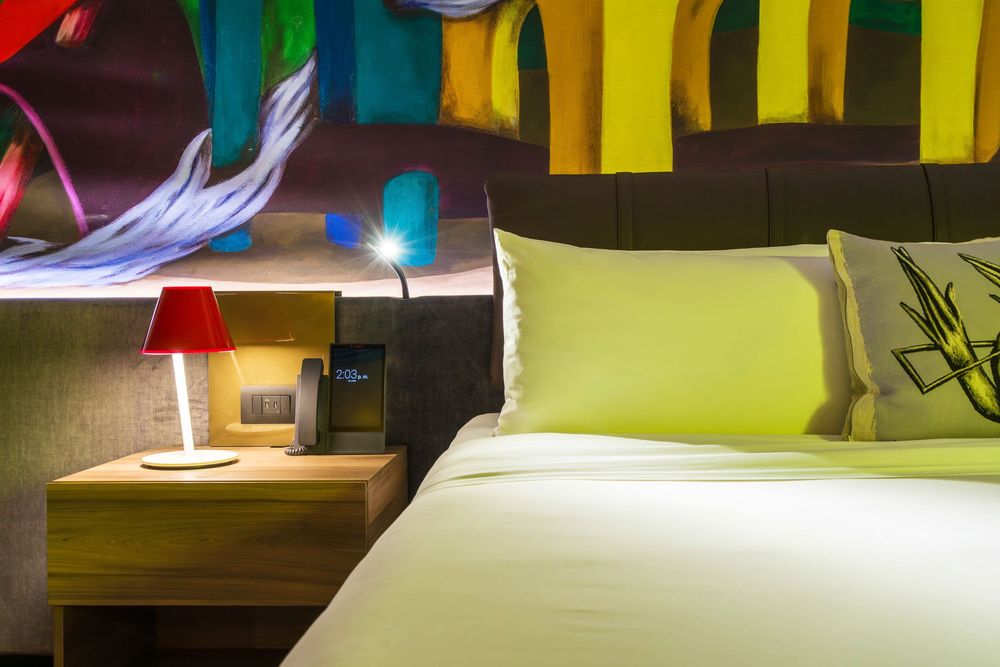 Colorful modern hotel interior design with bright yellow and green accent walls illuminated by contemporary lighting.