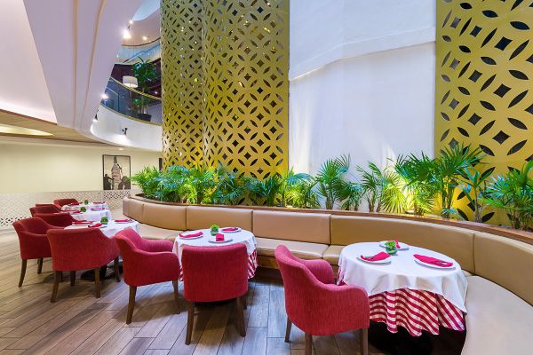 Modern restaurant Fontana Barcelo Mexico with red chairs and decorative gold lattice wall panels and tropical plants.