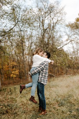 Playful couple dancing and twirling in a golden autumn field.