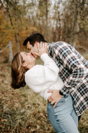 Romantic couple embracing and laughing together in a rustic outdoor setting.