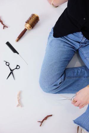 Professional hairdressing tools and blue denim jeans arranged on white background for beauty salon styling concept.
