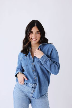 Person wearing double denim outfit poses against white background in studio setting.
