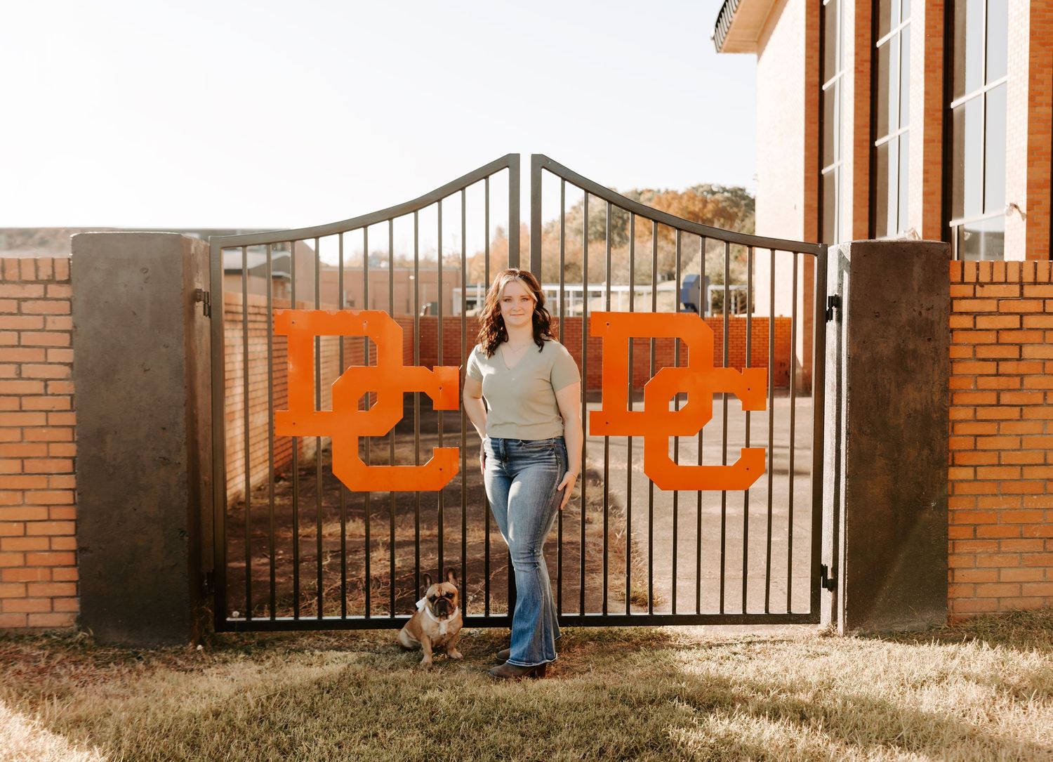 A casual portrait in front of an orange and black metal gate with text.