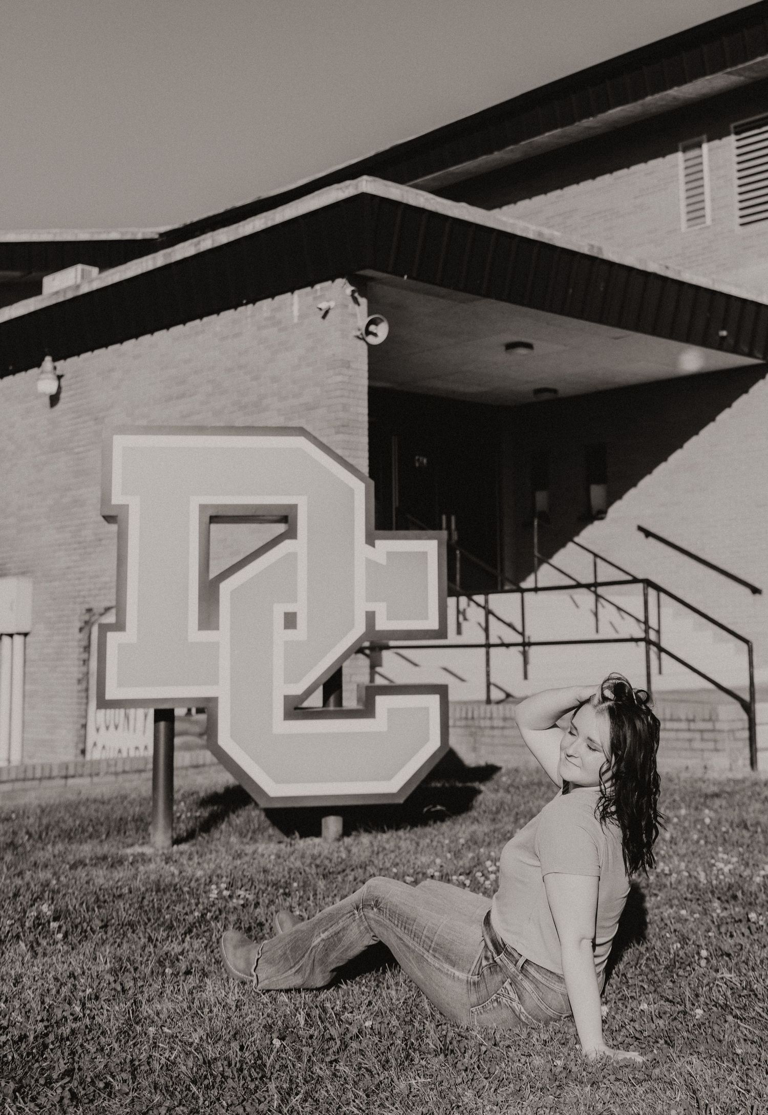 Black and white photo of someone posing by a large DC letter sign.