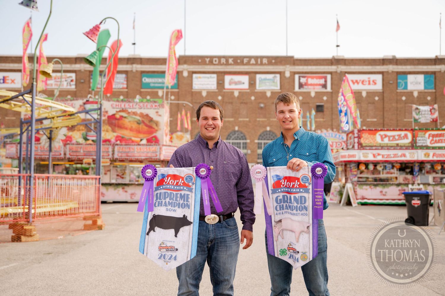 Two people display purple championship ribbons for livestock at county fair.
