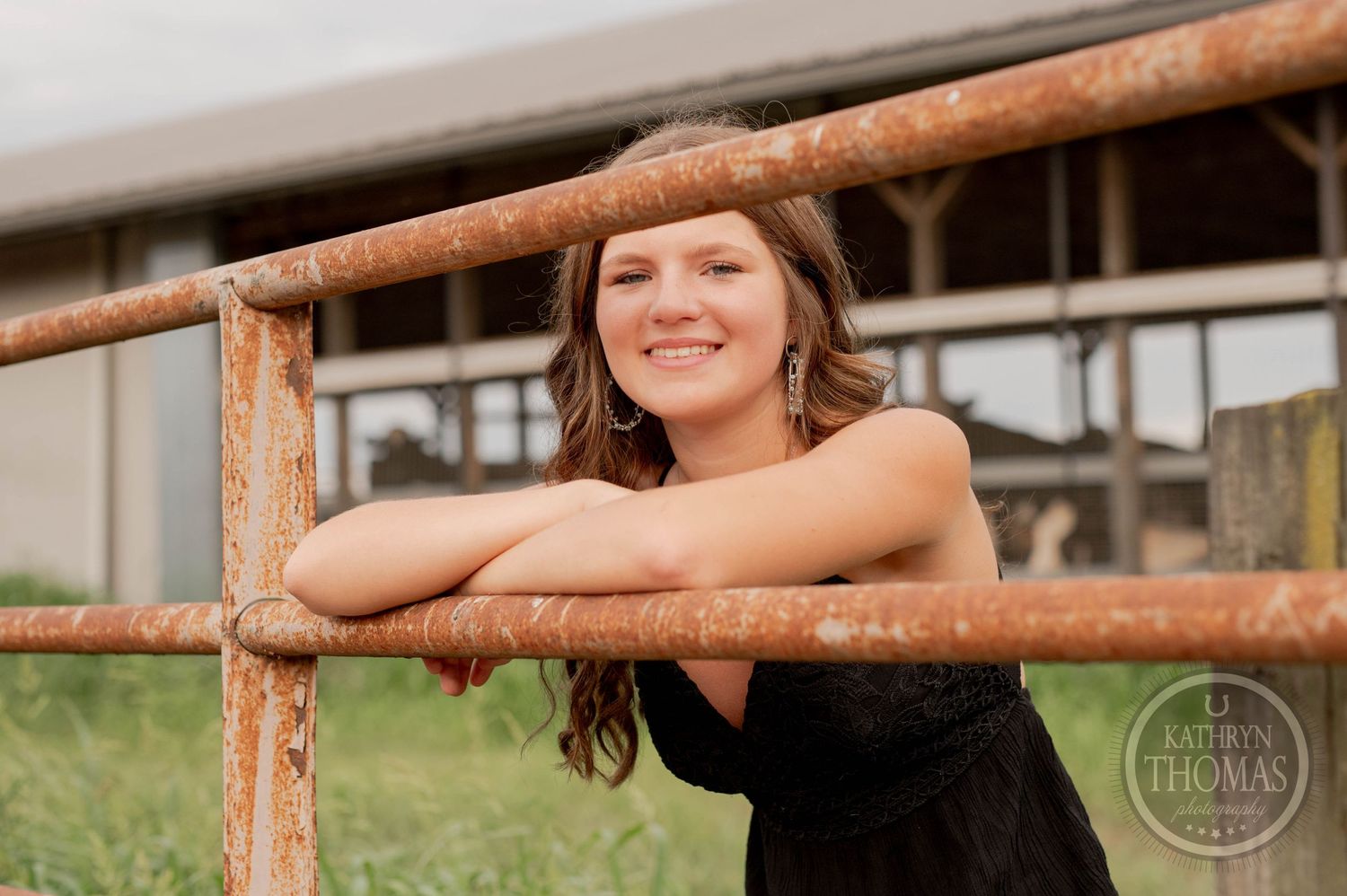 Rustic farm portrait leaning on wooden fence rail at sunset.