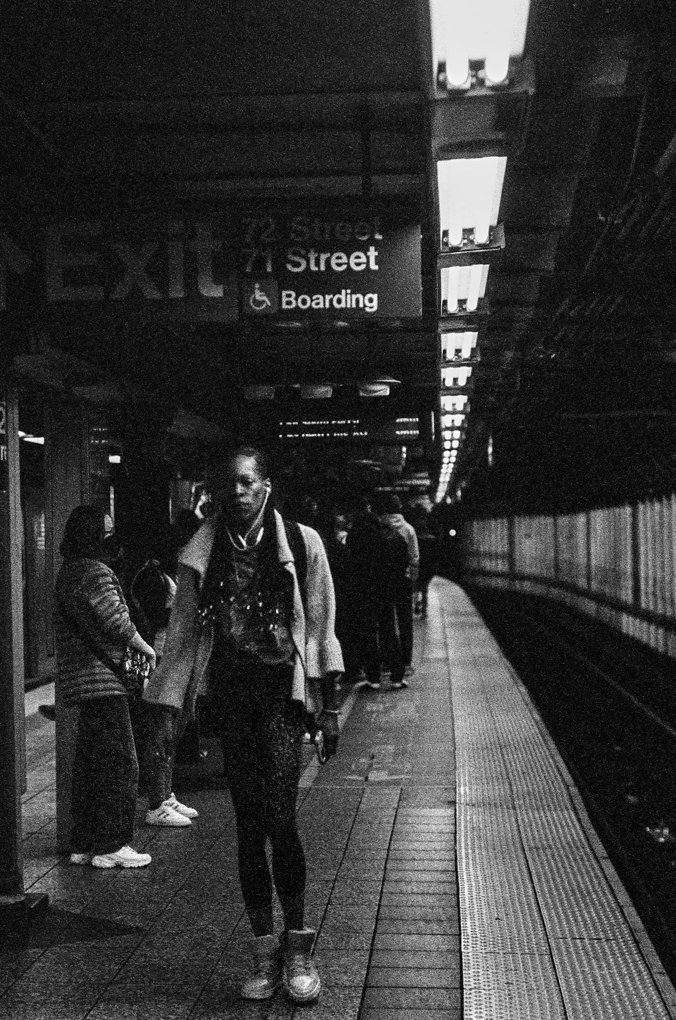 Underground subway platform with commuters waiting along a dimly lit corridor.