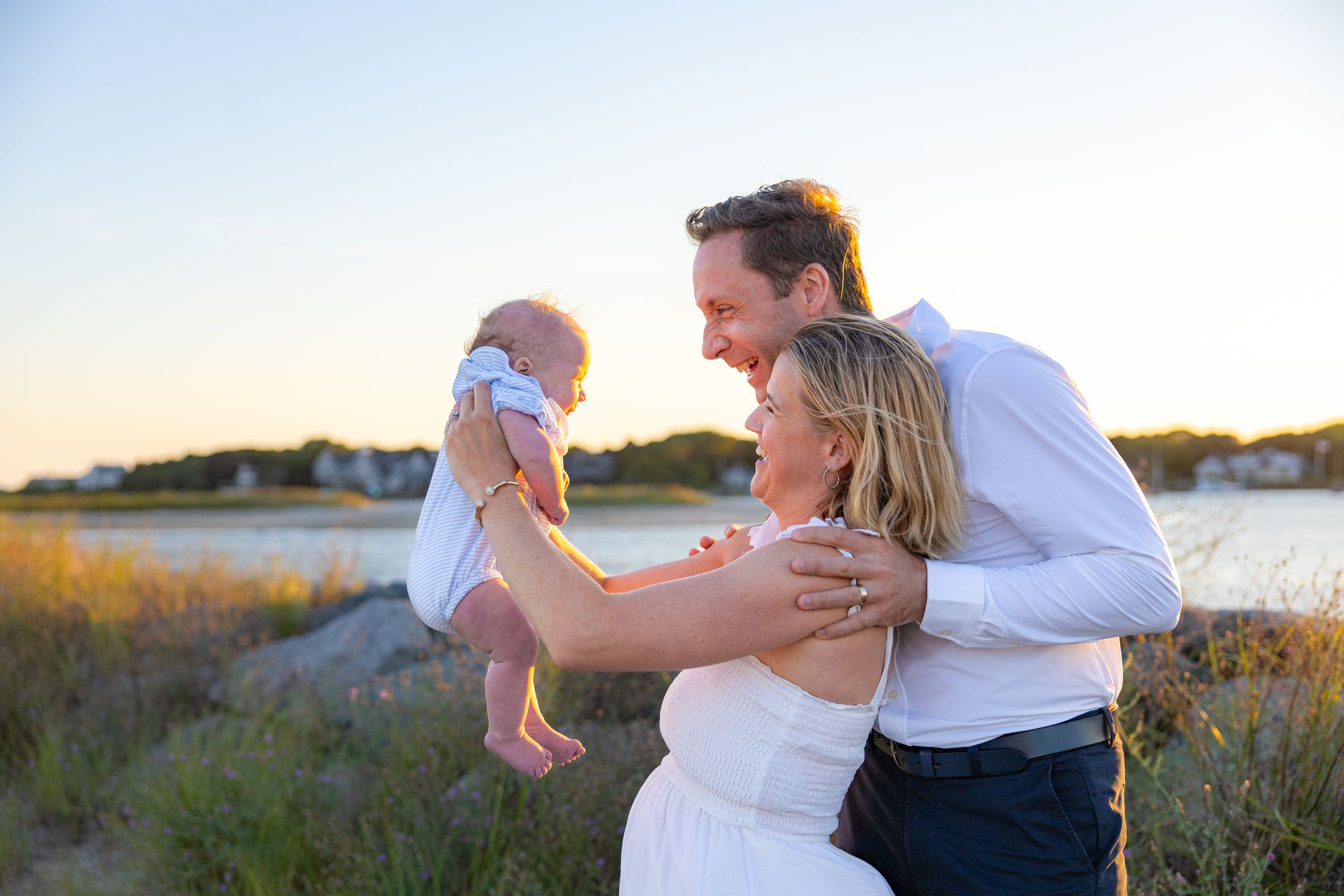Couple embraces on a beach at sunset during a romantic photoshoot session.