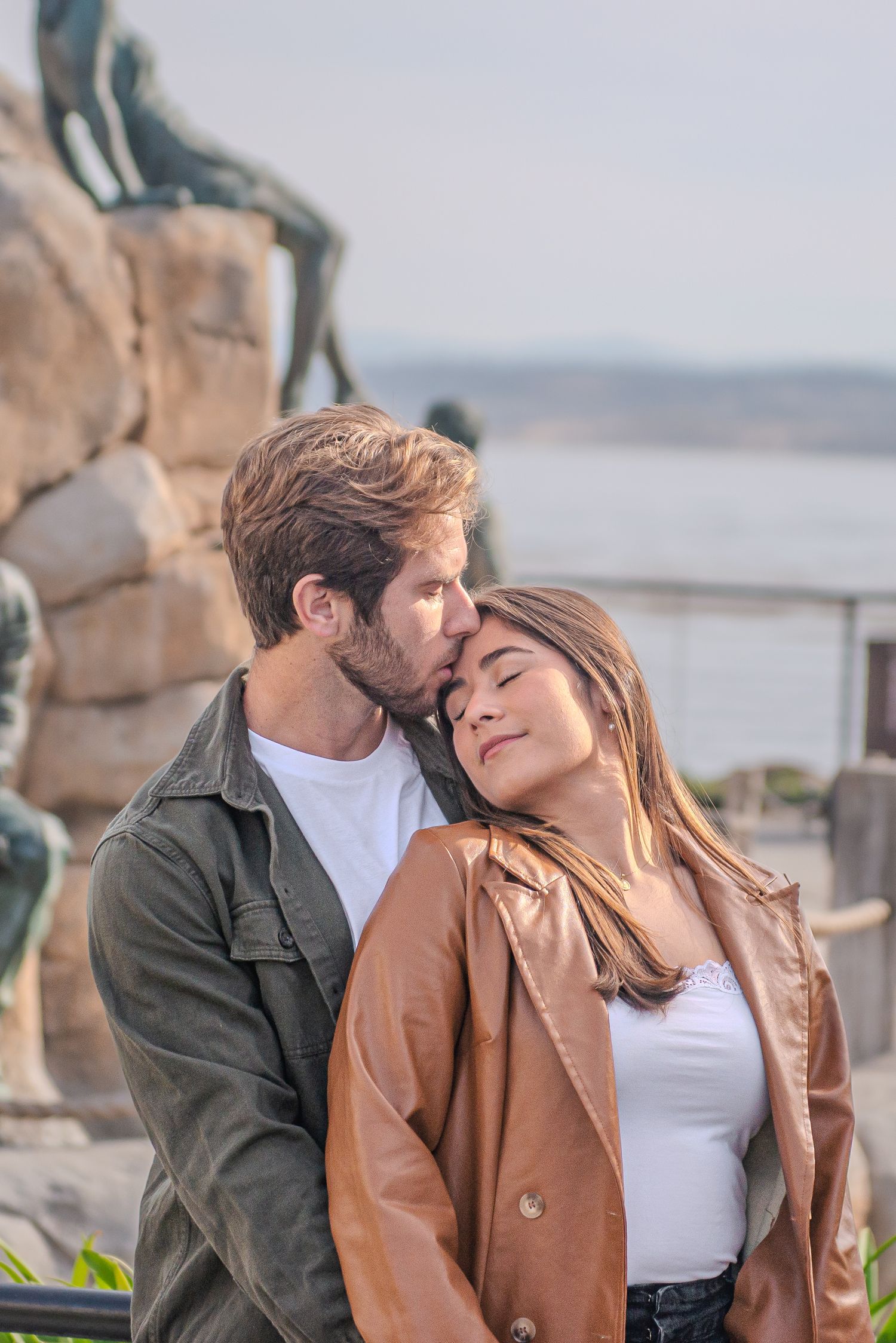 A couple shares a romantic moment near a coastal overlook.