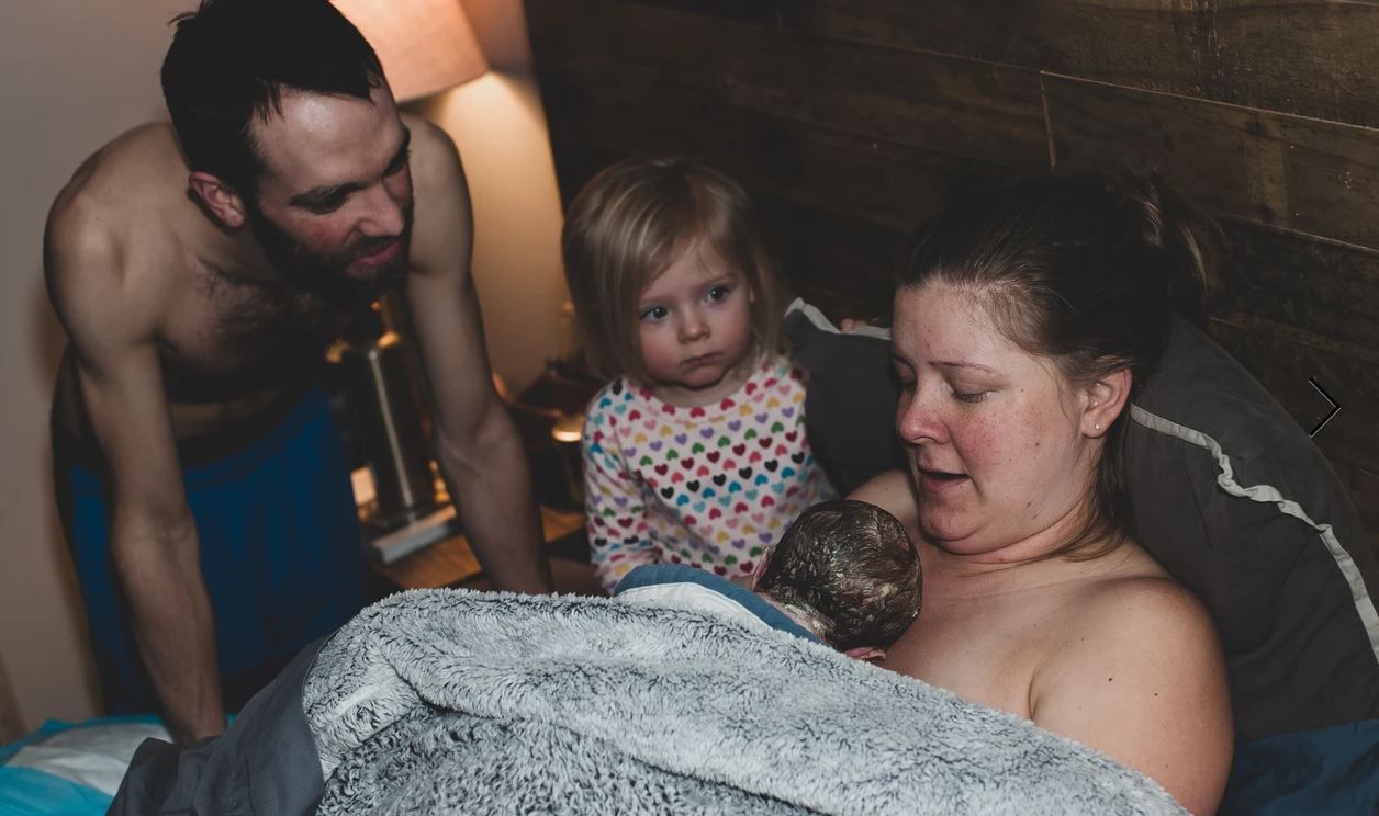 A family sharing an intimate moment during childbirth in a home setting.