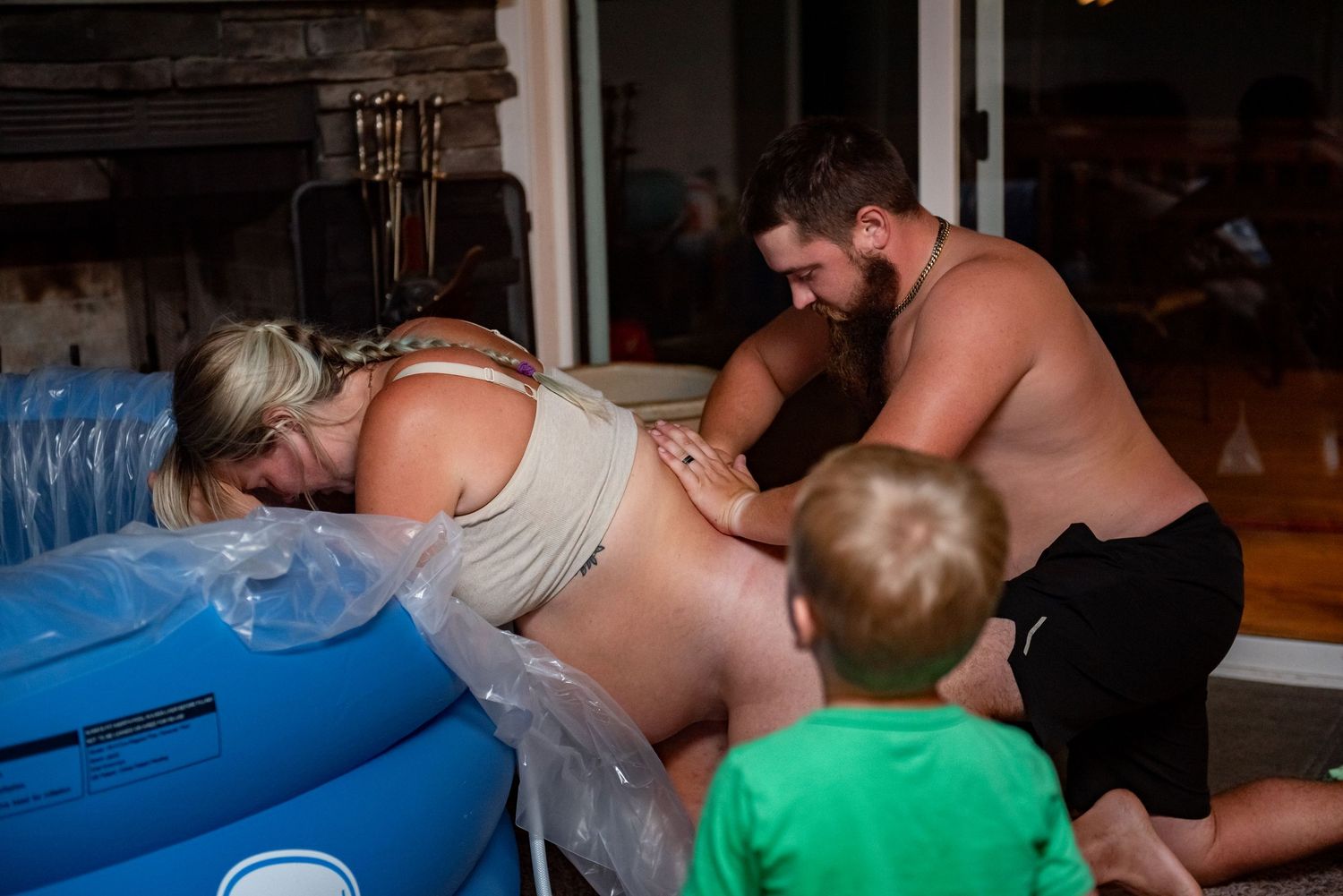 A group of people lean over a large inflatable pool during what appears to be an indoor gathering or party.