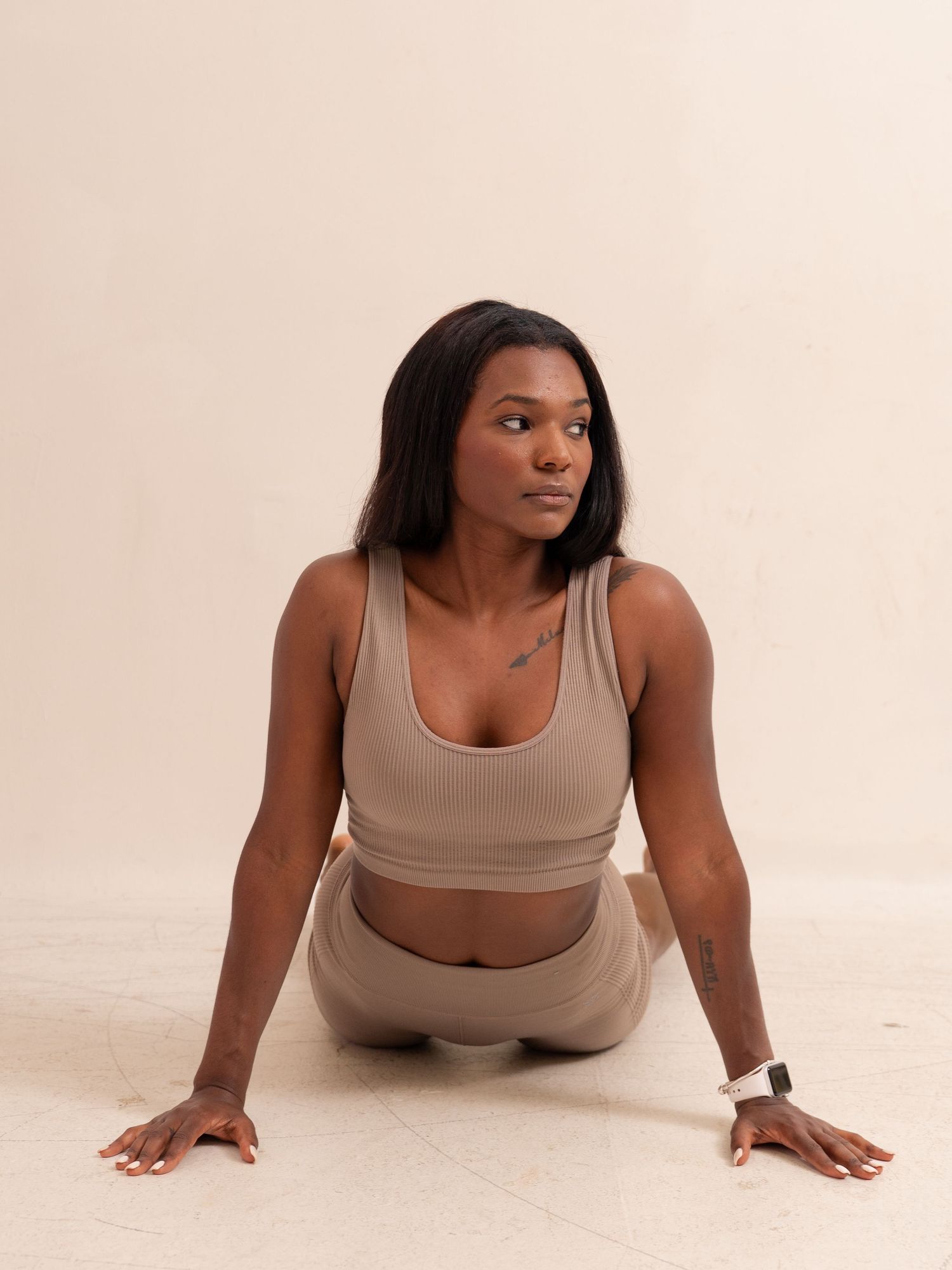 Athletic figure performing yoga poses in neutral-colored activewear against white background.