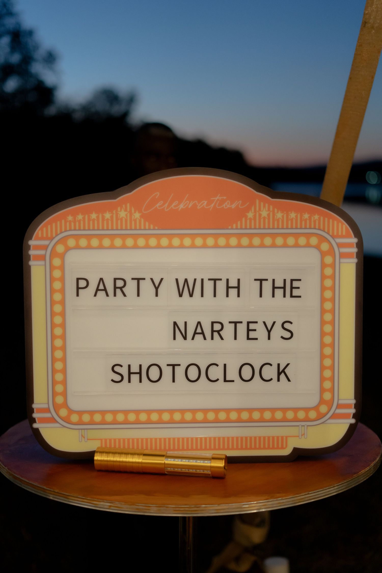 Decorative party sign reading Party With The Narteys Shotoclock on a ornate marquee-style display at dusk.