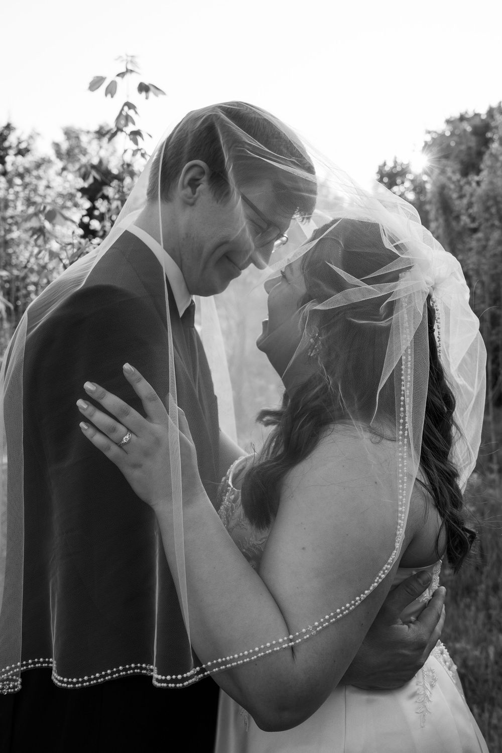©AnnaVonRiesenPhotography Bridal Portraits | B&W image of a couple smiling at each other under a veil.