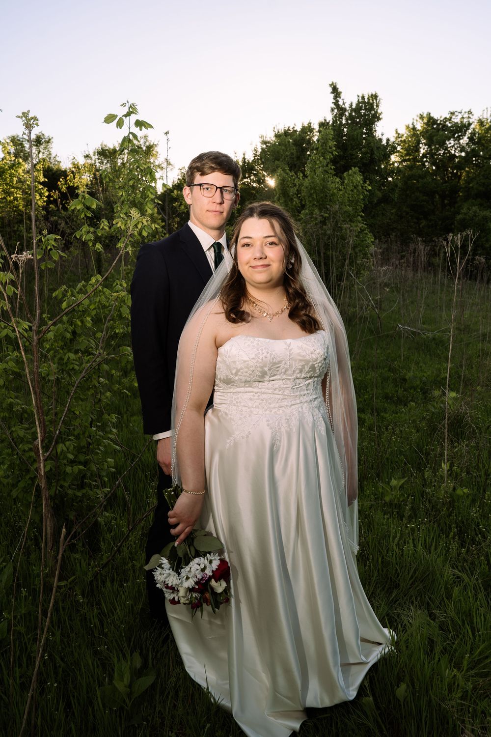 ©AnnaVonRiesenPhotography Bridal Portraits | Color image of a couple posing in a field.